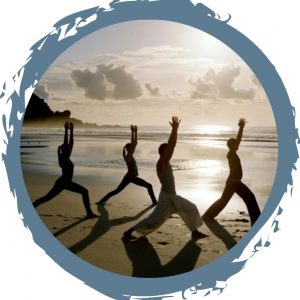 A picture of 4 people holding a yoga pose on the beach at sunrise